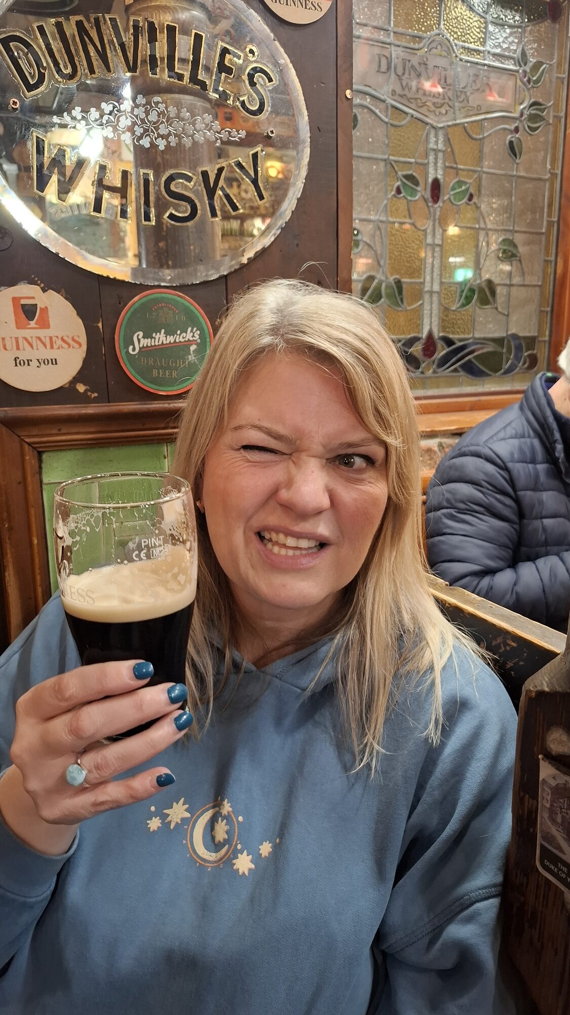 Mel with a Guinness under the Dunville&rsquo;s Whisky sign