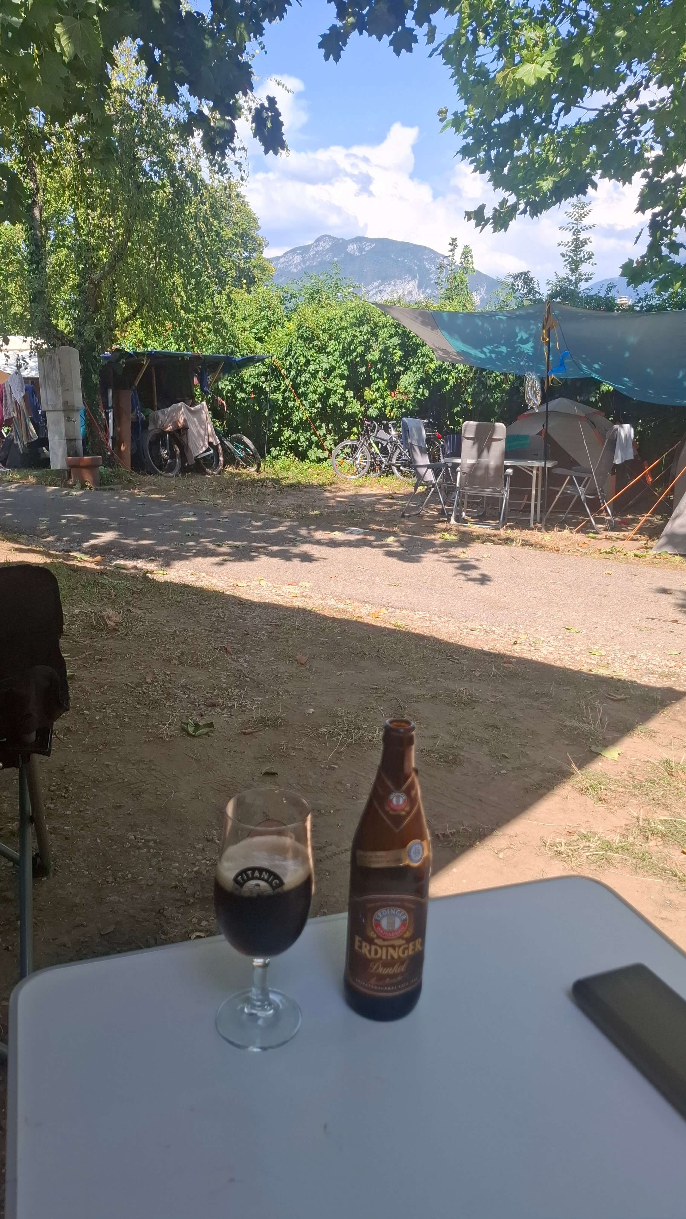 A well-earned beer, campsite and mountains behind